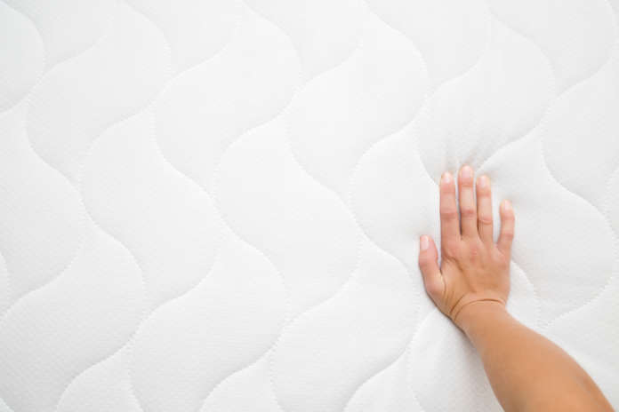 Woman's,Hand,Pressing,On,White,Mattress.,Checking,Hardness,And,Softness.